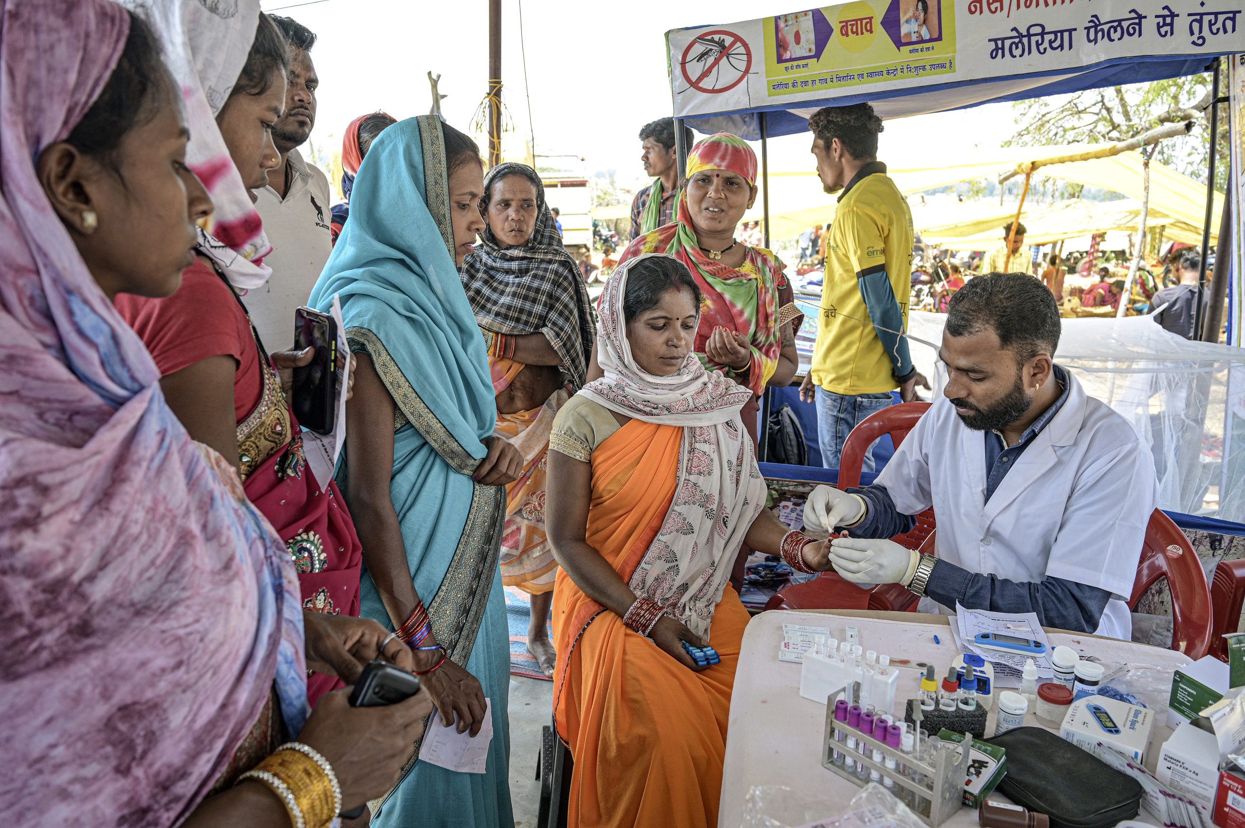 Visitors to a market in Binta village, Bastar district, have the opportunity to undergo tests for a number of health issues, including malaria and dengue. In recent years, India has made impressive gains in reducing its malaria burden, with cases dropping by more than 40% between 2015 and 2021. Most of the remaining cases are concentrated among tribal populations living in rural areas. This photo set describes efforts by local health workers to reach people at risk of malaria in remote areas of Chhattisgarh, a state that accounts for nearly one fifth of the countrys malaria burden. Related: https://www.who.int/news-room/photo-story/photo-story-detail/reaching-people-at-risk-of-malaria-in-remote-areas-of-Chhattisgarh-india